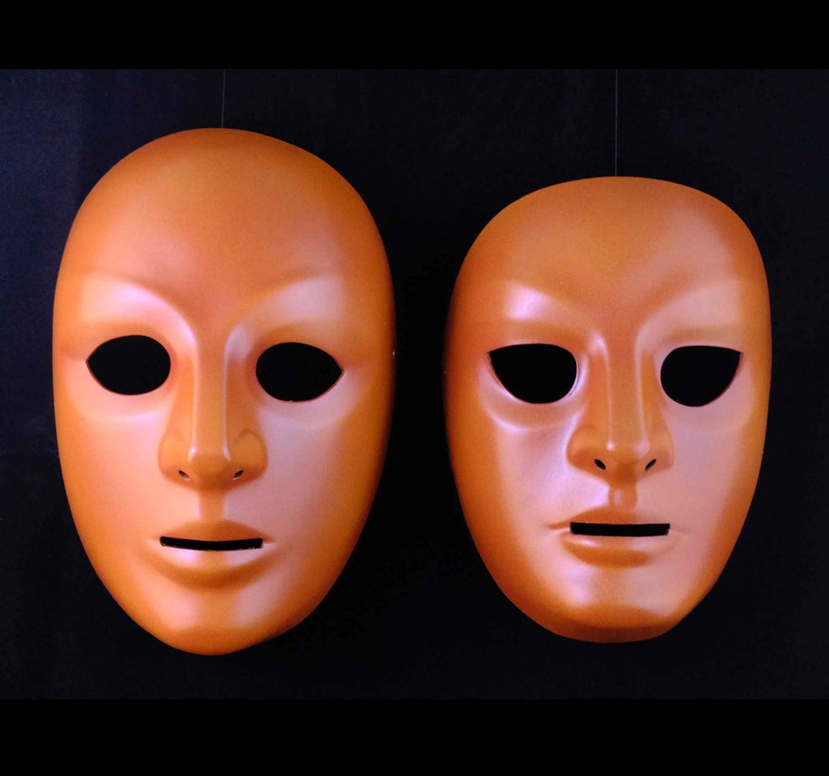 A close-up of a single Lecoq-style neutral mask, showing its smooth, featureless surface and subtle curvature. The mask appears to be made of leather, with a soft sheen that reflects light gently.
