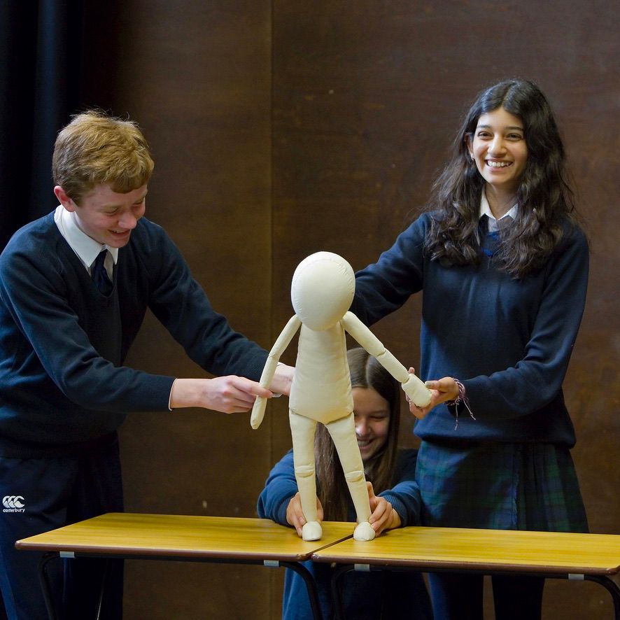 Three students puppeteering a neutral puppet